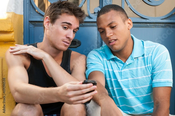 Obraz Young males having fun with a cellphone.