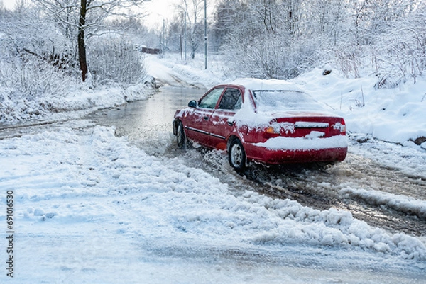 Obraz The car rides on a road with melted snow and ruts from the wheels in the spring