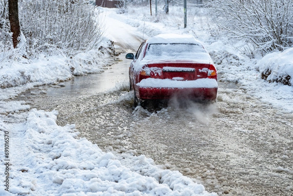 Obraz The car rides on a road with melted snow and ruts from the wheels in the spring