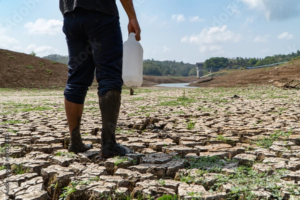Fototapeta a man looks for water in the midst of the El-Nino climate disaster causing drought at the Palasari dam, Jembrana, Bali. The dam water receded and the land became dry and fragmented