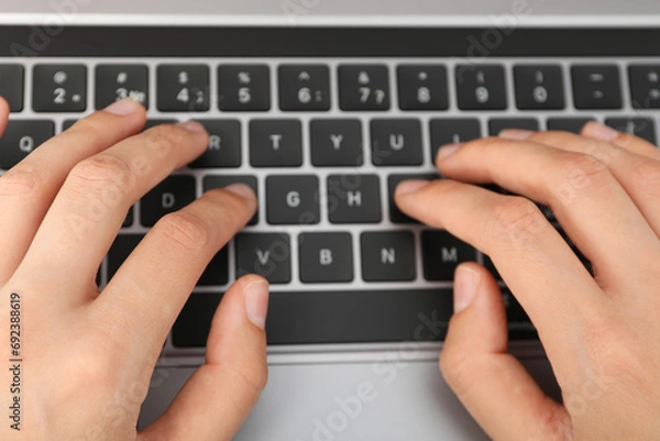 Fototapeta Hands on black laptop keyboard close up view