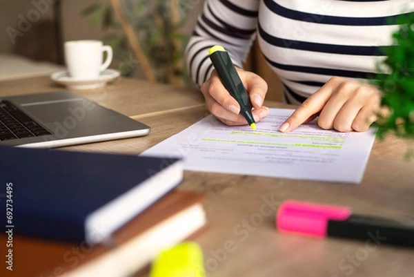 Obraz Unrecognizable businesswoman's hands highlighting important things on paper document.