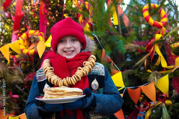 Fototapeta smiling boy going to eat pancakes  at the traditional Russian festival dedicated to the meeting of spring, the week of pancakes, Shrovetide. decorations for the Maslenitsa holiday