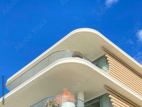 Fototapeta Summer white house on the beach with blue sky. Close-up of part of a house structure. Villa balconies and railings. Luxurious architecture. Exterior walls covered with lime.