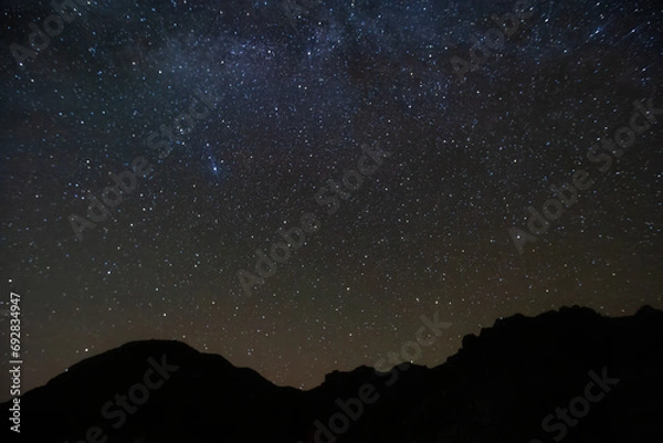 Obraz A scenic view of the Milky Way and starry night sky over the Chisos Mountains in Big Bend National Park, Texas.