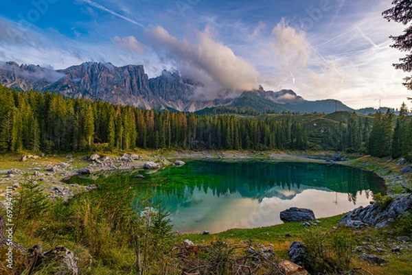 Obraz Lago di Carezza, resting at 1,519m, an alpine wonder with emerald waters, embraced by spruce trees, framed by the majestic Dolomites, a fairy tale unfolding in nature's enchanting panorama