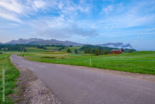Obraz Alpe di Siusi or Seiser Alm, Vast alpine meadows, rolling hills, and distant peaks bathed in golden sunrise