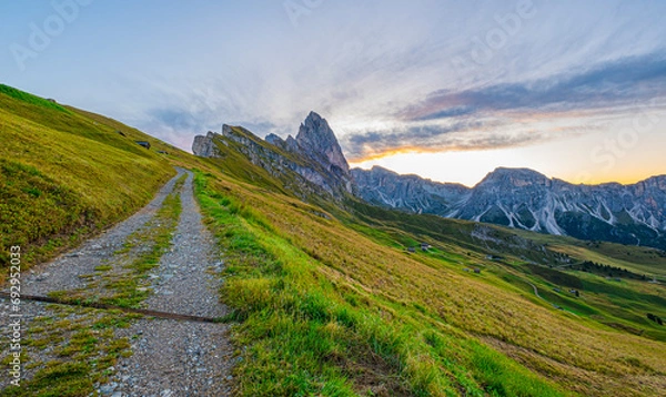 Obraz Golden sunrise at Seceda, Dolomites, Italy, illuminating the rugged landscape, casting a warm glow on the iconic peaks, and creating a serene morning spectacle.