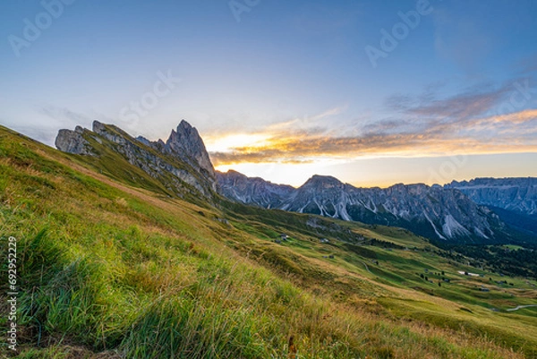 Obraz Golden sunrise at Seceda, Dolomites, Italy, A breathtaking spectacle unfolds, casting warm hues on the rugged landscape and meadows, creating a serene and radiant morning panorama.