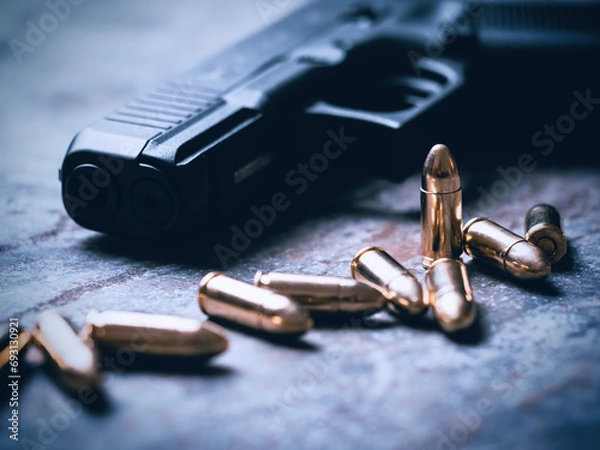 Fototapeta Hand gun with ammunition on dark background. 9 mm pistol military weapon and pile of bullets ammo at the metal table.