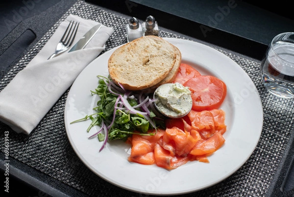 Obraz Breakfast with gravlax salmon, cream cheese, arugula salad and plain bagel on a serving tray 