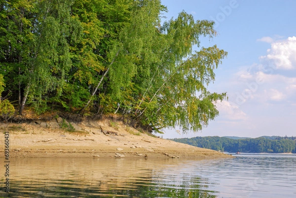 Fototapeta View of the water and the sandy shore of Lake Solina in summer. There is a forest around. Panorama of the Bieszczady Mountains, Poland.