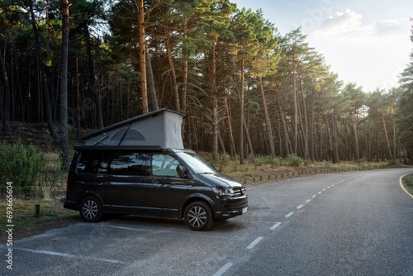 Obraz Modern new camper van with the roof open parked beside the forest in beautiful nature scene at sunset, Well Rope Reservoir, Soria, Spain
