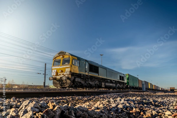 Fototapeta A UK freight train with locomotive and wagons transporting shipping container boxes
