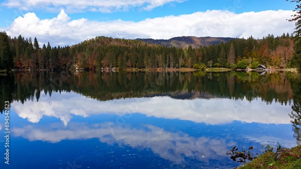 Fototapeta Panoramic view of Fusine Lake (Laghi di Fusine) in Tarvisio, Friuli-Venezia Giulia, Italy, Europe. Water reflection in clear green alpine lake. Autumn colored foliage. Calm serene tranquil atmosphere
