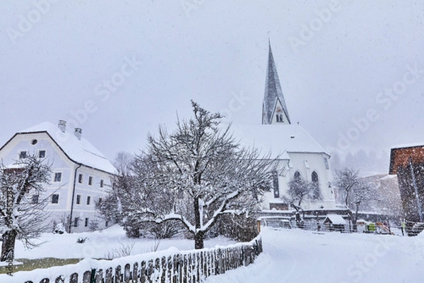 Fototapeta View of snow-covered Bramberg, with the village church in Salzburger Land, Austria,