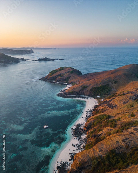 Fototapeta Aerial view of the coast of southern Lombok. A catamaran down at sea. Sunset. Indonesia