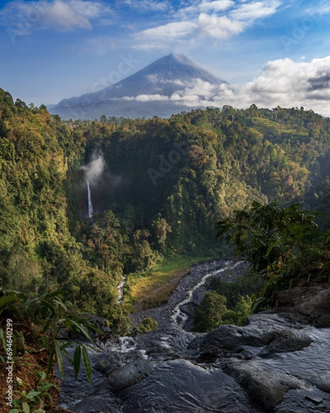 Fototapeta Panorama of the Kapas Biru waterfall in East Java, Indonesia. In the distance there is a jungle and the Seneru volcano.