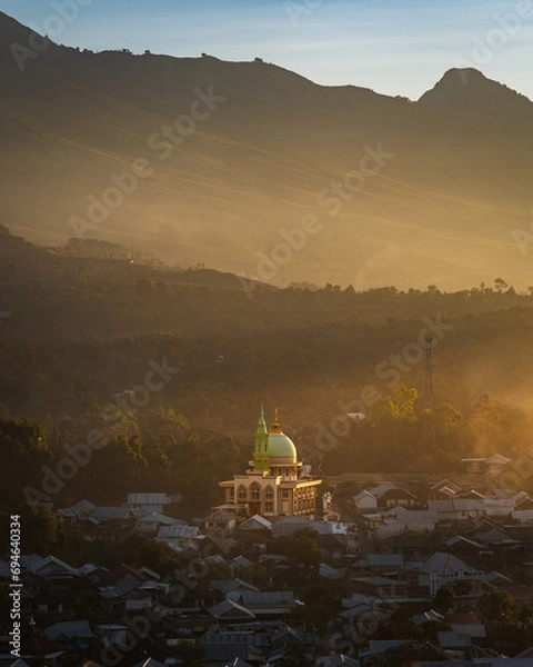 Fototapeta Sunset over the village of Sambaloen. Golden hour. Mosque in the foreground. Around the buildings. Lombok. Indonesia