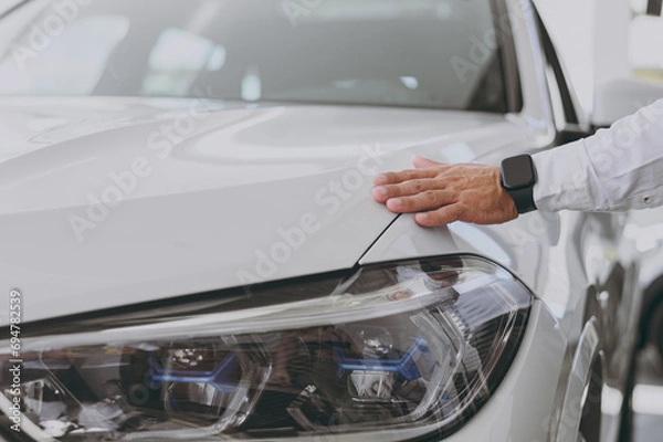 Fototapeta Close up cropped male customer buyer client open touch gently puts hand on car hood check paint choose auto want buy new automobile in showroom vehicle salon dealership store motor show Sales concept