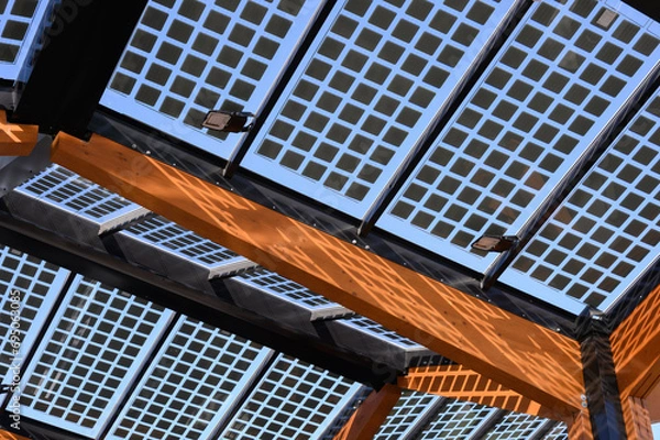 Obraz The photovoltaic roof of an electric charging station at a roadside car park. The supporting structure is made of wood.