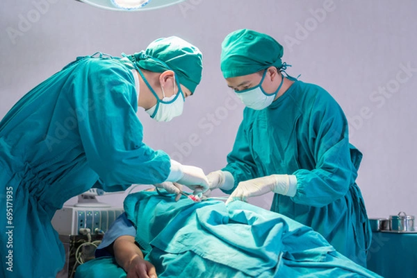 Fototapeta Medical team performing surgical operation in operating Room, Concentrated surgical team operating a patient