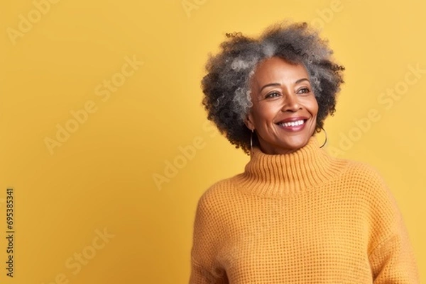 Fototapeta Portrait of a content afro-american woman in her 70s dressed in a warm wool sweater against a pastel yellow background. AI Generation