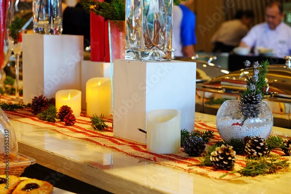 Fototapeta Candles and conifer fruit decoration on Christmas event in a dining place