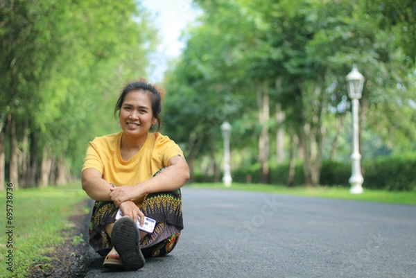 Fototapeta Beautiful smiling Asian woman in the park green trees in spring nature background