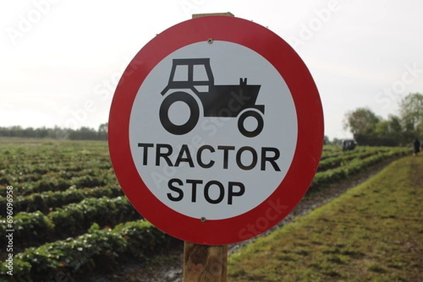 Fototapeta Round sign "Tractor Stop" with tractor symbol, taken outdoors in a field