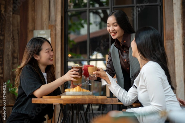 Obraz A group of trendy, happy Asian girls are drinking and enjoying talking in a cafe in the city.