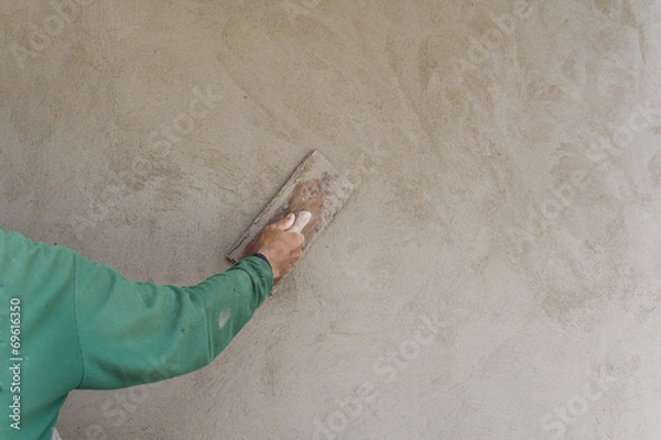 Fototapeta Worker wearing green shirts are using plastering gaskets to plaster the walls with copy space in construction work or house.