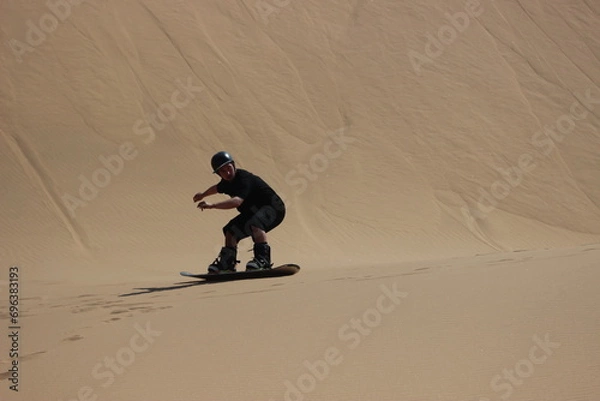 Fototapeta Sandboarding over a dune in the Namibian Desert
