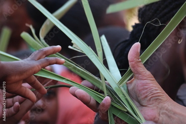 Fototapeta Priests hand handing out palm leaves during religious ceremony to childs hand