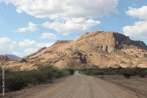 Fototapeta Street view from a car on a sand road with a desert mountain in Namibia

