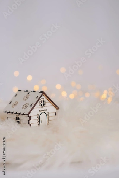 Fototapeta Miniature wooden house on white fur background with bokeh lights