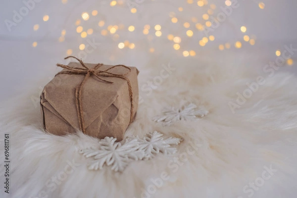 Fototapeta Christmas gift box on a white fur background with bokeh lights