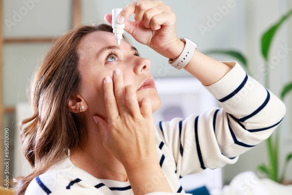 Fototapeta Young woman putting eye drops