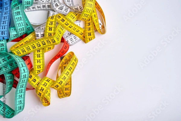 Fototapeta Multi-colored measuring tapes on a light background. Tool for measuring length and volume. Tape for measuring in sewing production or the volume of the human body