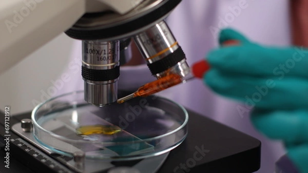 Fototapeta laboratory setting with colorful liquids in test tubes and a person wearing a lab coat and gloves.