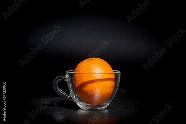 Fototapeta Round orange on a black background, orange for juice, citruses