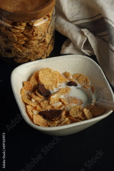 Obraz Bowl of cereal, cornflakes with milk in a bowl on a black background