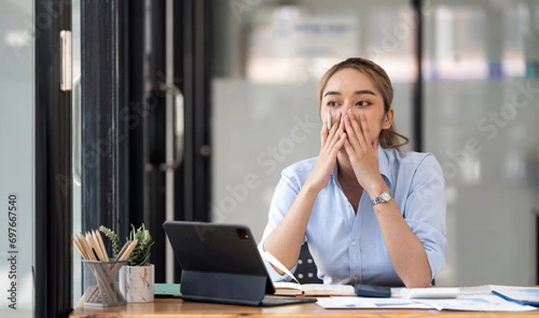 Obraz Stressed woman with mouth in hand leaning on table at home office.