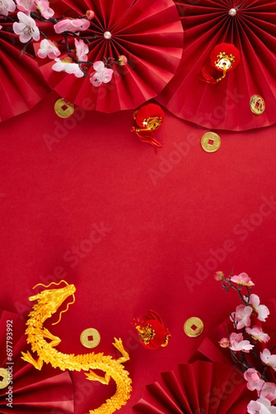 Obraz Decorating for Chinese New Year concept. Top view vertical photo of gold dragon, paper fans, lucky coins, decorative elements, sakura on red background with advert space