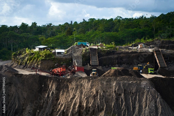 Fototapeta A stone quarry in Indonesia. Large equipment such as bulldozers and dump trucks are working on the site.