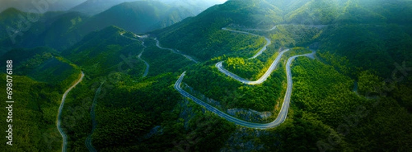 Fototapeta Top view from drone of mountain road in woods in a summer day.