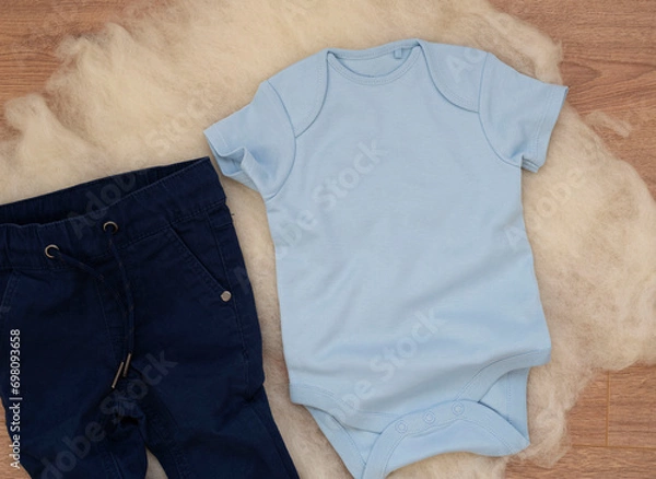 Fototapeta Mockup of blue baby bodysuit on wood background with jeans. Blank baby clothes template mock up. Flat lay styled stock photo.