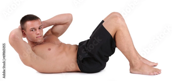 Fototapeta Handsome young muscular sportsman execute exercise isolated