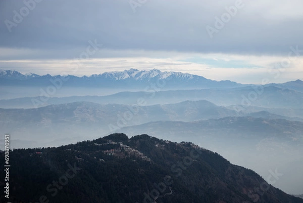 Obraz Clouds over snow covered mountains with trees