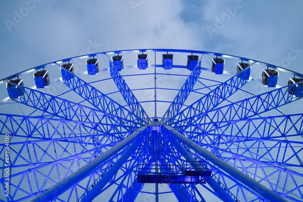 Fototapeta Underside view of colorful ferris wheel over evening sky at amusement park.